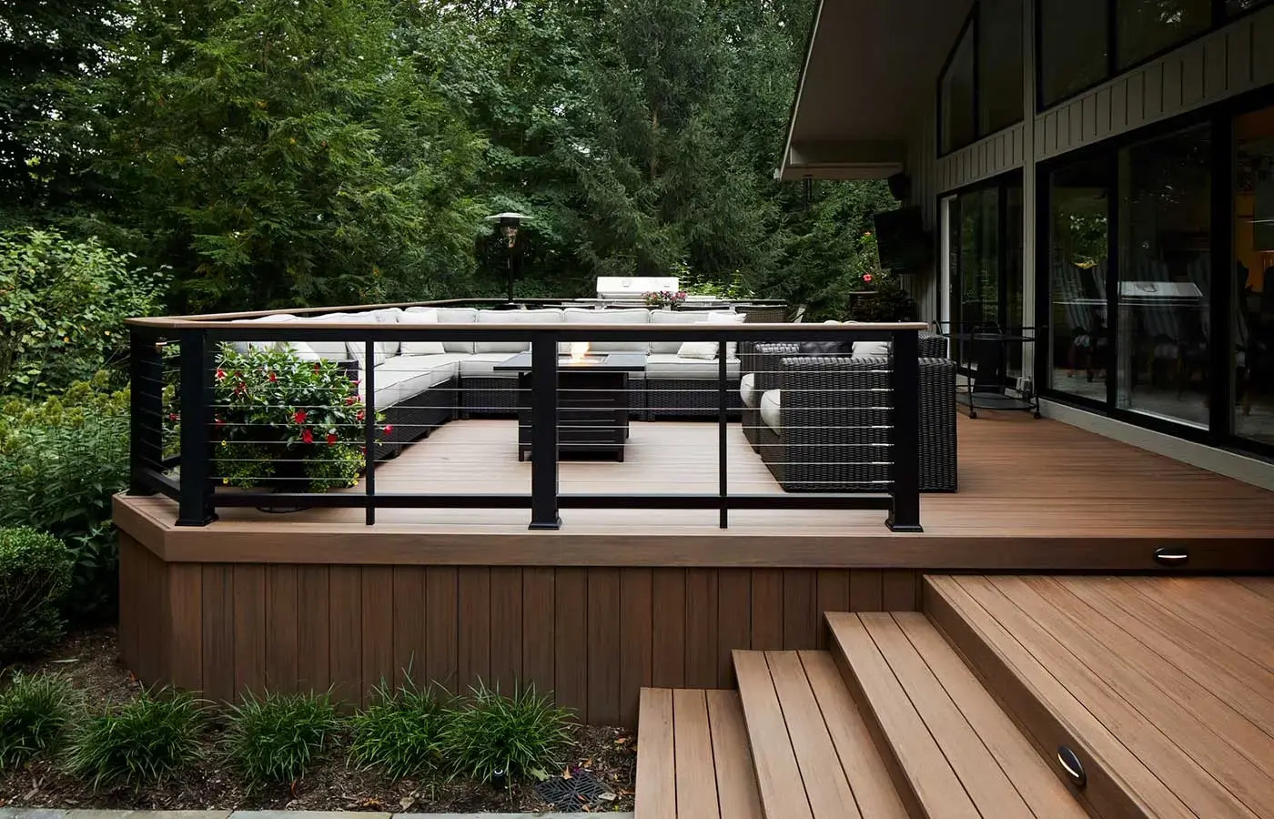 custom-english-walnut-vintage-pvc-deck-with-cable-railings-and-lights-on-deck-steps-featuring-outdoor-living-fire-place-surrounded-by-big-trees-on-the-background-in-tacoma-wa
