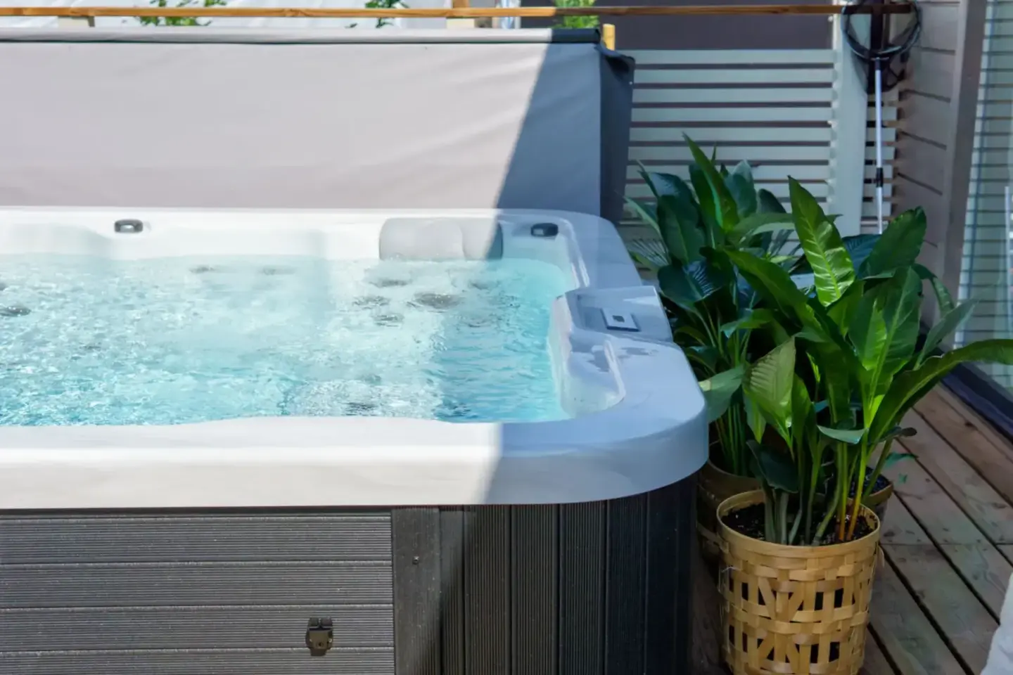 outdoor-hot-tub-on-wooden-deck-with-potted-plants-and-white-privacy-screen-on-the-background-in-tacoma-wa